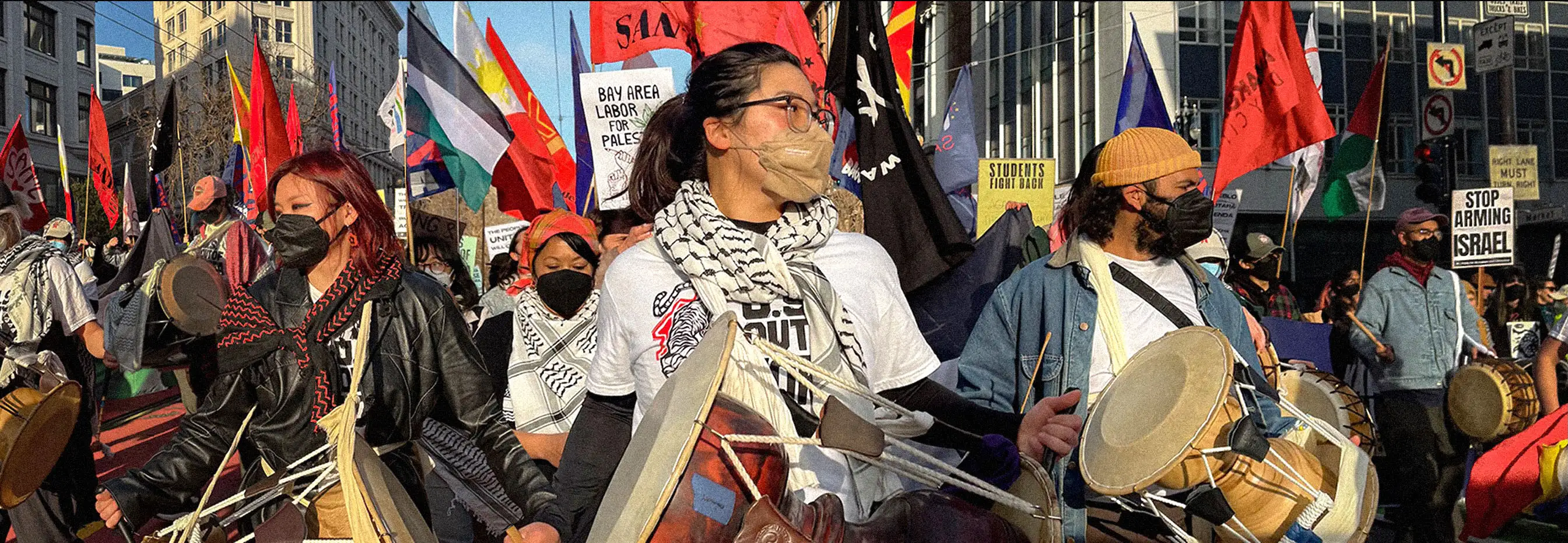 Wide shot of people drumming as part of a larger mobilization.